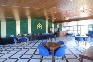 a restaurant with blue chairs and tables and a green wall at Cosmos Resort Maliblu in Indore