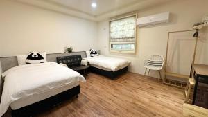 een slaapkamer met twee bedden en een raam bij Honey B&B in Hualien