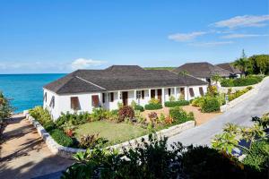 a house with a garden in front of the ocean at French Leave Resort, Autograph Collection in Governorʼs Harbour