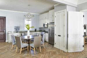 a kitchen with a table and chairs and a kitchen with white cabinets at French Leave Resort, Autograph Collection in Governorʼs Harbour