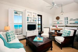 a living room with white furniture and a tv at French Leave Resort, Autograph Collection in Governorʼs Harbour