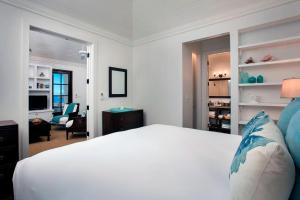 a bedroom with a white bed and a living room at French Leave Resort, Autograph Collection in Governorʼs Harbour