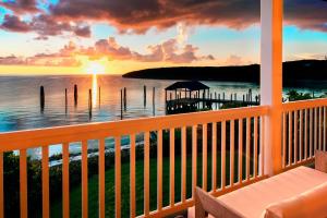 a view of the ocean from a porch with a sunset at French Leave Resort, Autograph Collection in Governorʼs Harbour