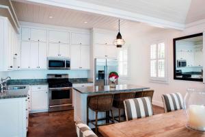 a kitchen with white cabinets and a wooden table at French Leave Resort, Autograph Collection in Governorʼs Harbour