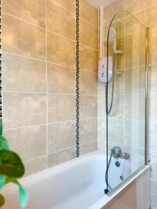 a bathtub with a glass shower door in a bathroom at King's Cottage in Tassagh +10 photos