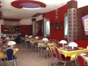 a dining room with tables and chairs and red walls at Hotel Silver Oak in Ooty