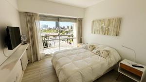 a white bedroom with a bed and a large window at Depto Varese - Depto Vista al Mar Zona Varese Para 3 PAX Con Cochera - Hola Sur in Mar del Plata