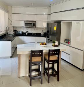 una cocina con una isla con 2 sillas y un bol de fruta en Garzota Suites Airport Bajos, en Guayaquil