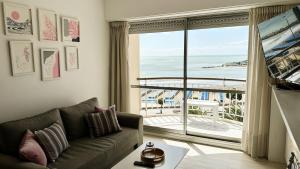 a living room with a couch and a view of the ocean at Depto Varese - Depto Vista al Mar Zona Varese Para 3 PAX Con Cochera - Hola Sur in Mar del Plata