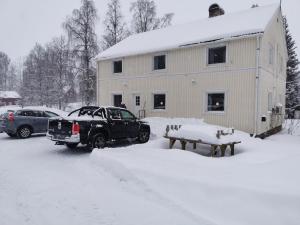 a truck parked in the snow in front of a house at Guldklimpens Vandrarhem in Gunnarn