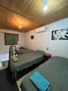 Una habitación con dos camas y techo de madera. en Hospedaje Río, en Río Primero