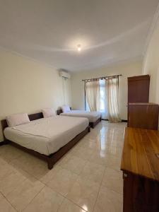 a bedroom with two beds and a window at d'Alvin Double Room in Labuan Bajo