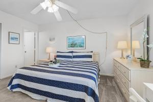 - une chambre blanche avec un lit rayé bleu et blanc dans l'établissement Lake Access, Community Pool, Tennis & Pickleball -Condo Lagoon Landing -Roelens, à Fort Myers Beach 21 autres photos