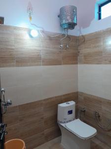 a bathroom with a toilet and a light on the wall at Riya Home Stay in Sawāi Mādhopur