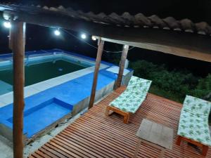 a deck with two chairs and a swimming pool at night at Bellas cabañas valle hermoso in Valle Hermoso