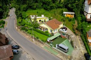 a large yellow house with a green yard at VELINN Pousada Casa de Campos Capivari House in Campos do Jordão