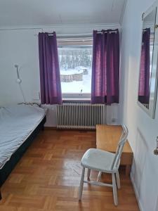 a bedroom with a bed and a chair and a window at Guldklimpens Vandrarhem in Gunnarn