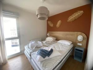 Un dormitorio con una cama con sábanas y almohadas blancas. en L'orée Royannaise, en Royan