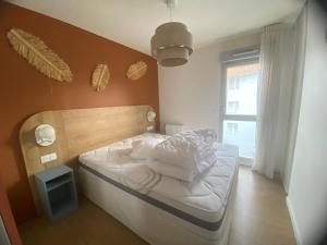Un dormitorio con una cama con cabecero de madera. en L'orée Royannaise, en Royan