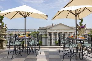 two tables and chairs with umbrellas on a patio at Market Pavilion Hotel in Charleston
