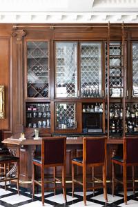 a bar in a restaurant with wooden cabinets and chairs at Market Pavilion Hotel in Charleston