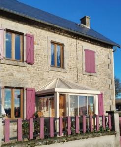 a brick house with pink shutters and a fence at Maison de vacances ou chambres d'hôtes belle campagne auvergnate in Saint-Julien-la-Geneste
