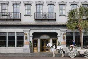 a man riding a horse drawn carriage in front of a building at Market Pavilion Hotel in Charleston