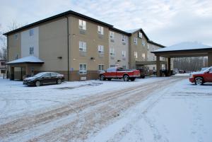 a snow covered parking lot in front of a building at Paradise Inn and Suites Redwater in Redwater