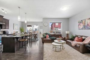 ein Wohnzimmer und eine Küche mit einer Couch und einem Tisch in der Unterkunft Large Family 4BR w Kid's Play Den! Near Airport & Shopping! FREE Banff Pass, BBQ, Netflix, Parking & Wine! in Calgary