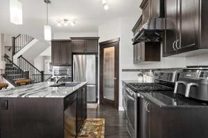 eine Küche mit Küchengeräten aus Edelstahl und Holzschränken in der Unterkunft Large Family 4BR w Kid's Play Den! Near Airport & Shopping! FREE Banff Pass, BBQ, Netflix, Parking & Wine! in Calgary