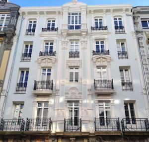 a large white building with balconies and windows at Apartamentos Ovetum in Oviedo