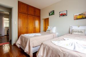 a bedroom with two beds and a wooden cabinet at Apto 2 suítes no Bueno, perto do Goiânia Shopping in Goiânia