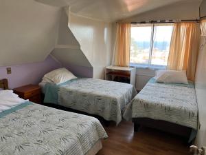 a small room with two beds and a window at Altos de Miramar in Puerto Montt