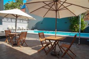 two tables and chairs with umbrellas next to a pool at ISONDU Suites & Breakfast in Puerto Iguazú