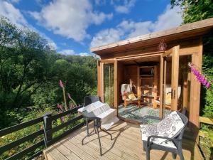 eine Holzterrasse mit einem kleinen Schuppen mit Stühlen darauf in der Unterkunft Cosy Cottage overlooking the Teifi Gorge in Cilgerran