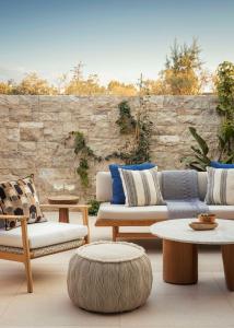 a patio with couches and tables and a stone wall at One&Only Aesthesis, Athens in Athens