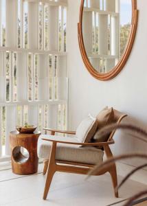 a living room with a chair and a mirror at One&Only Aesthesis, Athens in Athens