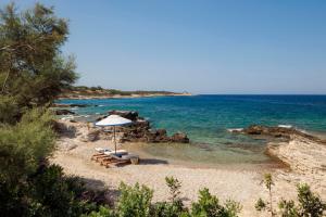 a beach with a bench and an umbrella on the sand at One&Only Aesthesis, Athens in Athens