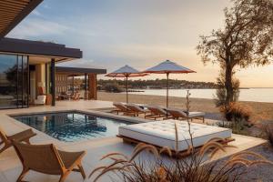 a pool with chairs and umbrellas next to a house at One&Only Aesthesis, Athens in Athens