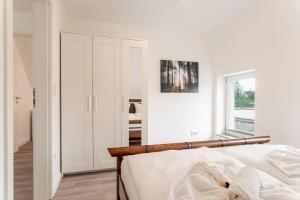 a white bedroom with a bed and a window at Ostseebad-Zinnowitz-Kernsanierte-Maisonette-Wohnung-Himmel in Zinnowitz