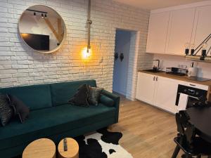 a living room with a green couch and a kitchen at Apartament SMALL Czarny Potok in Krynica Zdrój