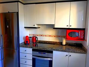 a kitchen with white cabinets and a red microwave at Playa Daimus 100 m del Mar Piscina Parking in Daimuz