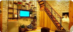 a living room with a staircase and a television at Ela's Chalet in Old Bazaar Gjirokaster in Gjirokastër