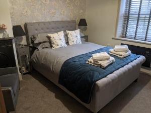 Schlafzimmer mit einem Bett mit blauer Bettwäsche und Kissen in der Unterkunft 1 Hillside Cottages in Leeds