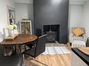 ein Wohnzimmer mit einem Tisch und einem Holzofen in der Unterkunft 1 Hillside Cottages in Leeds