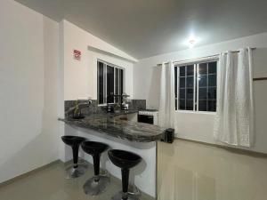 a kitchen with three bar stools and a counter at Darwin's Hideaway in Puerto Baquerizo Moreno