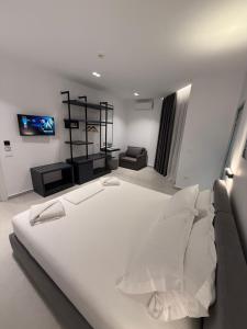 a bedroom with a large white bed and a tv at Adele Hotel Ksamil in Ksamil