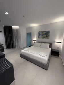 a white bedroom with a bed and a desk at Adele Hotel Ksamil in Ksamil