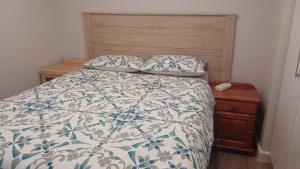 a bed with a blue and white comforter and a wooden headboard at 202 Mossel Cove in Mossel Bay