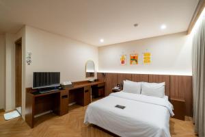 a bedroom with a bed and a desk with a television at Hotel Laglas Asan in Asan